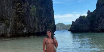 Mujer en bikini en la playa entre acantilados.