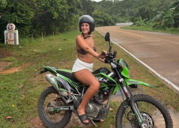 Mujer joven sentada en una motocicleta verde en Tailandia.