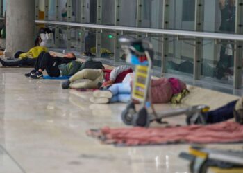 Gente que duerme en el piso de una terminal del aeropuerto.