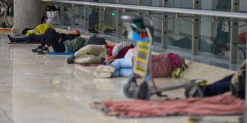 Gente que duerme en el piso de una terminal del aeropuerto.