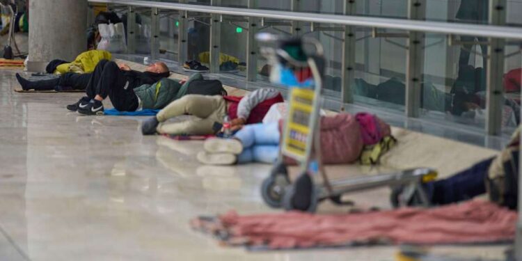 Gente que duerme en el piso de una terminal del aeropuerto.