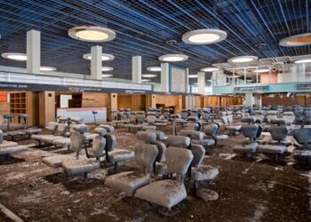 Sala de espera del aeropuerto abandonada con asientos sucios.