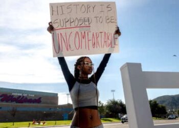 Un estudiante tiene un letrero que lee "Se supone que la historia es incómoda" En protesta por la prohibición del distrito de la teoría de la raza crítica del plan de estudios en Great Oak High School en Temecula, California, el 16 de diciembre de 2022.