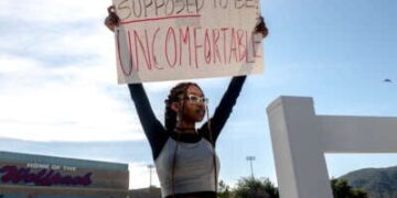 Un estudiante tiene un letrero que lee "Se supone que la historia es incómoda" En protesta por la prohibición del distrito de la teoría de la raza crítica del plan de estudios en Great Oak High School en Temecula, California, el 16 de diciembre de 2022.
