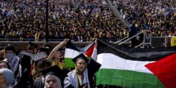 Salma Hamamy, centro, posee una bandera de Palestina durante la ceremonia de inicio de primavera de la Universidad de Michigan el 4 de mayo de 2024 en el estadio de Michigan en Ann Arbor, Michigan.
