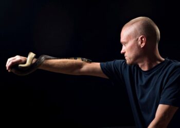 Hombre con hiperinmunidad al veneno de serpiente sosteniendo una cobra de agua.