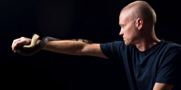 Hombre con hiperinmunidad al veneno de serpiente sosteniendo una cobra de agua.