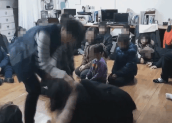 Una persona que interactúa con un grupo de niños sentados en el piso.