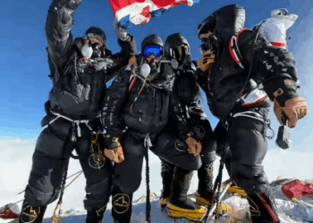 Escaladores en una cima de una montaña sosteniendo una bandera británica.