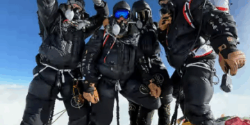 Escaladores en una cima de una montaña sosteniendo una bandera británica.