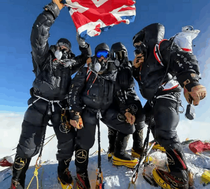 Escaladores en una cima de una montaña sosteniendo una bandera británica.