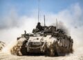 Tanque del ejército israelí que se mueve a lo largo de la frontera, pateando polvo.