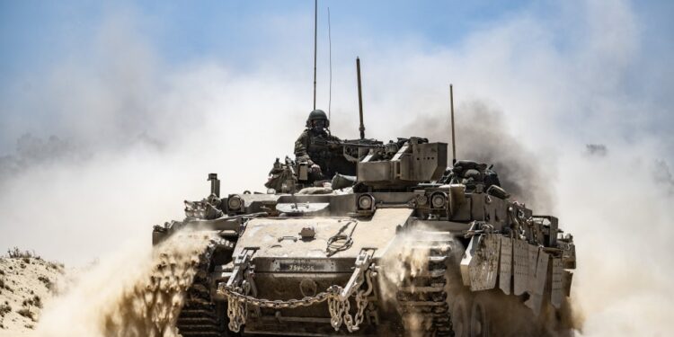 Tanque del ejército israelí que se mueve a lo largo de la frontera, pateando polvo.