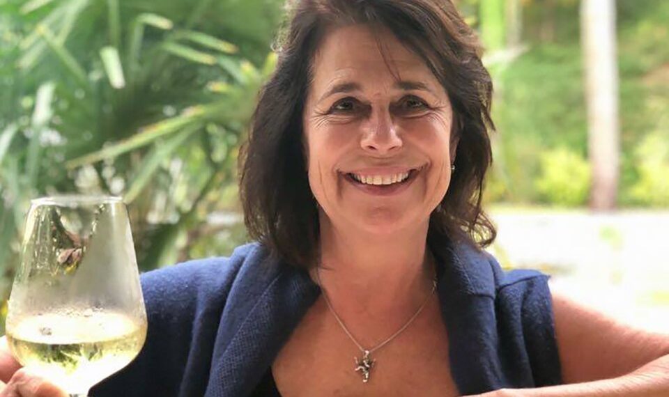 Mujer sosteniendo una copa de vino blanco.