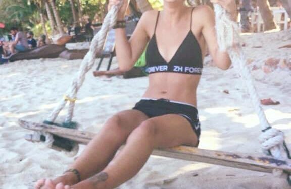 Mujer en un columpio de cuerda en una playa.