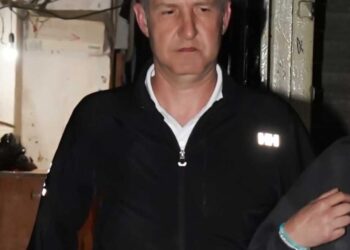 Un hombre con una chaqueta con cremallera negra dejando una oficina de abogados.