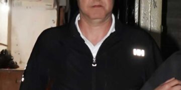 Un hombre con una chaqueta con cremallera negra dejando una oficina de abogados.