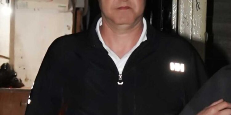 Un hombre con una chaqueta con cremallera negra dejando una oficina de abogados.