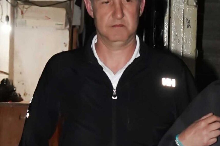 Un hombre con una chaqueta con cremallera negra dejando una oficina de abogados.