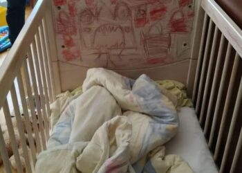 Una cuna con dibujos para niños en la cabecera y ropa de cama dentro.