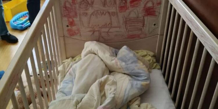Una cuna con dibujos para niños en la cabecera y ropa de cama dentro.