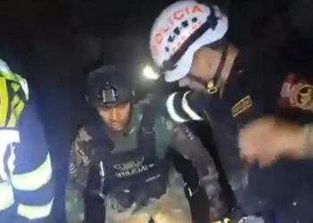 Personal de seguridad que ayuda a una persona en un entorno oscuro.