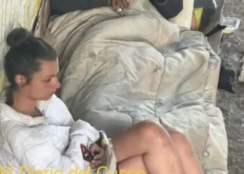 Dos personas durmiendo en el suelo, cubiertas por una manta.