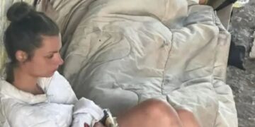 Dos personas durmiendo en el suelo, cubiertas por una manta.