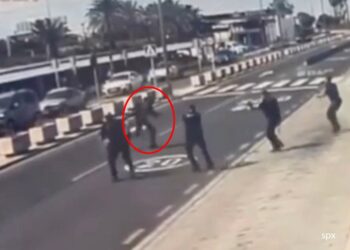 Oficiales de policía disparando a un hombre en un aeropuerto.