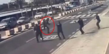 Oficiales de policía disparando a un hombre en un aeropuerto.