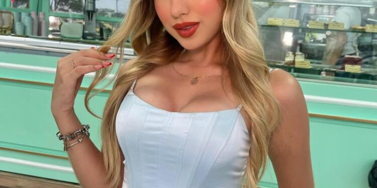 Retrato de una mujer joven en una parte superior del corsé azul claro y pantalones blancos.