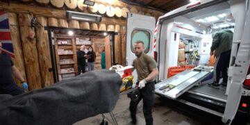 Los paramédicos cargan una camilla en una ambulancia.