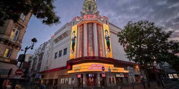 El cine Grand Rex en París al anochecer, que muestra un cartel de películas de My Hero Academia.