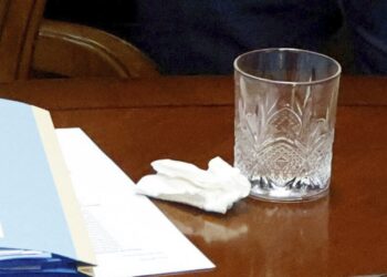 Imagen de un pañuelo, papeles y un vaso en una mesa.