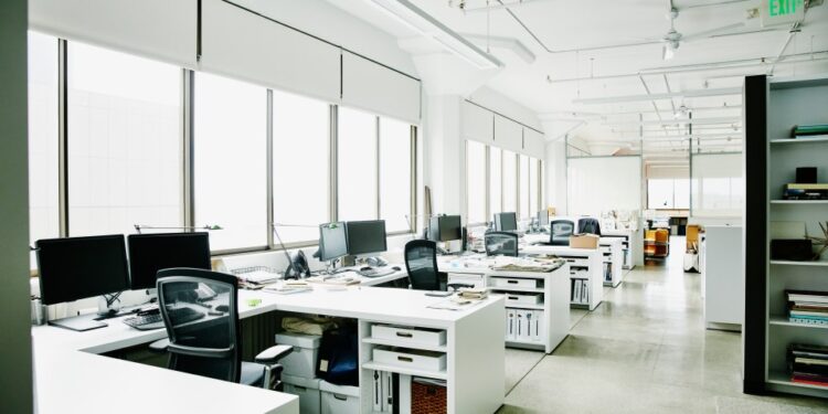 Oficina vacía con múltiples escritorios y computadoras.
