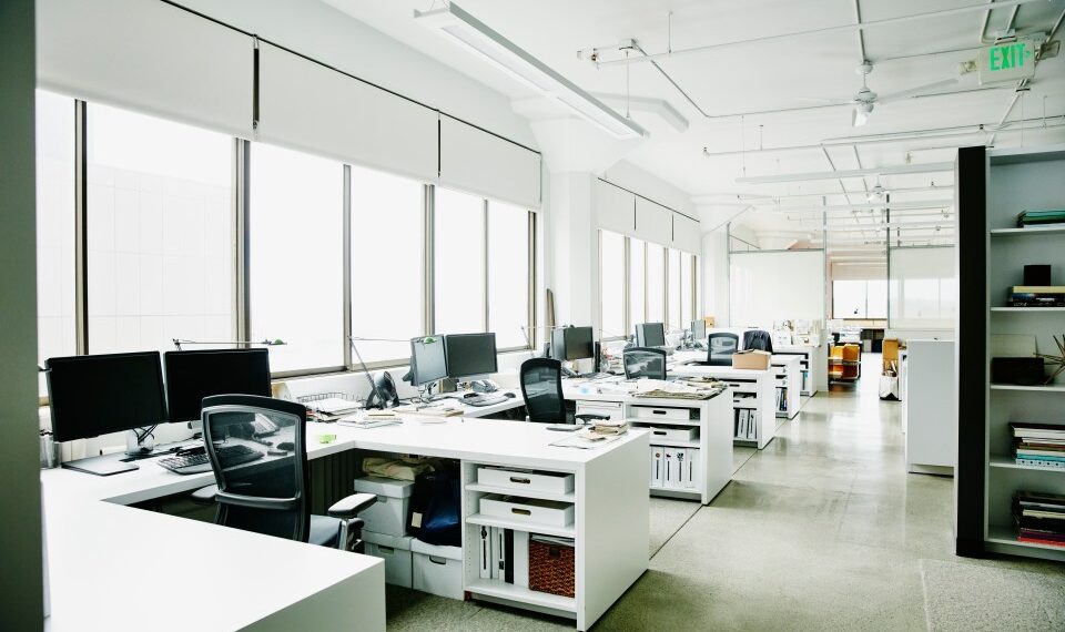 Oficina vacía con múltiples escritorios y computadoras.