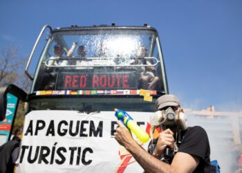 Los manifestantes que bloquean un autobús turístico con un banner leyendo "Vamos a apagar el fuego turístico".