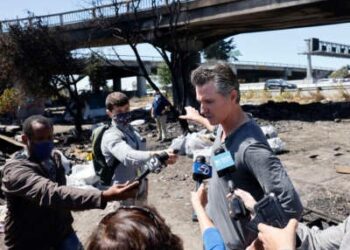 El gobernador de California, Gavin Newsom, habla con los medios de comunicación mientras participa en un barrido en un campamento de personas sin hogar de larga data a lo largo de la autopista 80 el 9 de agosto de 2021 en Berkeley, California.