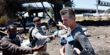 El gobernador de California, Gavin Newsom, habla con los medios de comunicación mientras participa en un barrido en un campamento de personas sin hogar de larga data a lo largo de la autopista 80 el 9 de agosto de 2021 en Berkeley, California.