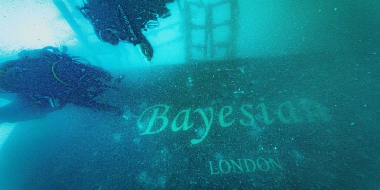 Foto submarina de buzos explorando el yate bayesiano hundido.