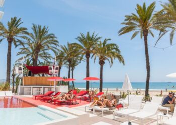 Gente que se relaja junto a una piscina en un hotel junto a la playa.
