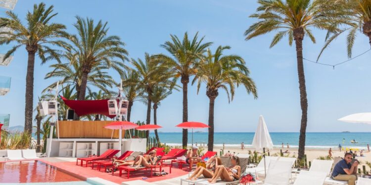 Gente que se relaja junto a una piscina en un hotel junto a la playa.