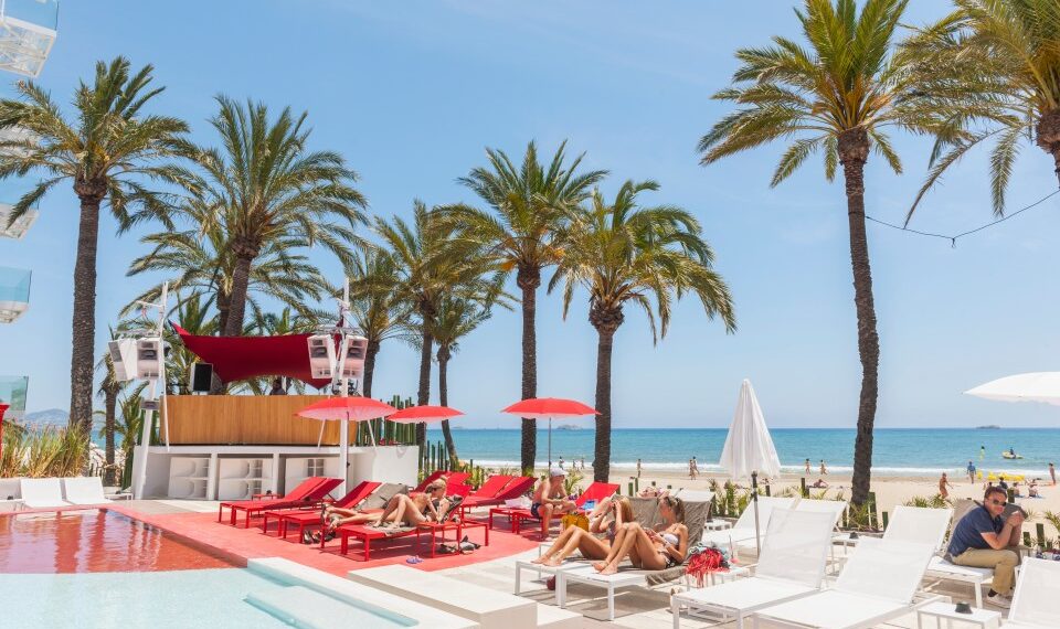 Gente que se relaja junto a una piscina en un hotel junto a la playa.