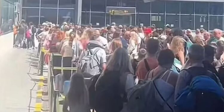 Gran multitud de personas que esperaban en una larga fila en un aeropuerto.