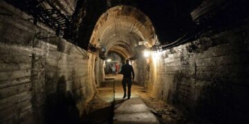 Un hombre camina por un túnel con poca luz.