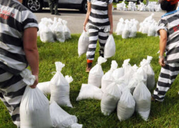 Un equipo de trabajo supervisado de prisioneras de la cárcel llena sacos de arena en preparación para la llegada del huracán Dorian en Florida el 29 de agosto de 2019.