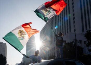 La gente agita las banderas mexicanas de sus autos durante una protesta al aire libre