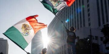 La gente agita las banderas mexicanas de sus autos durante una protesta al aire libre