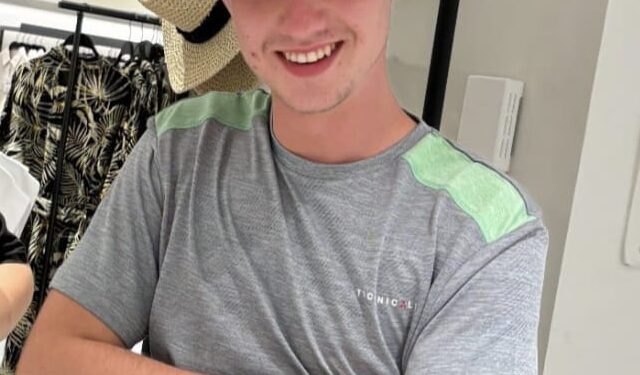 Foto de Jay Slater con una camisa gris y un sombrero de paja.