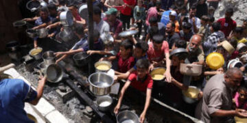 Los palestinos desplazados se reúnen para recolectar porciones de alimentos cocinados en una distribución de caridad en Jabalia en la franja del norte de Gaza el 19 de mayo de 2025.